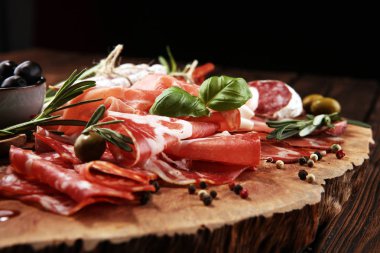 Jambon, pastırma, salam ve sosis ahşap arka plan üzerinde mermer kesme tahtası. Et tabağı meze ve zeytin