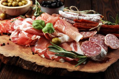 Jambon, pastırma, salam ve sosis ahşap arka plan üzerinde mermer kesme tahtası. Et tabağı meze ve zeytin