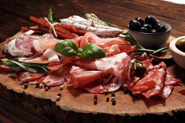Jambon, pastırma, salam ve sosis ahşap arka plan üzerinde mermer kesme tahtası. Et tabağı meze ve zeytin