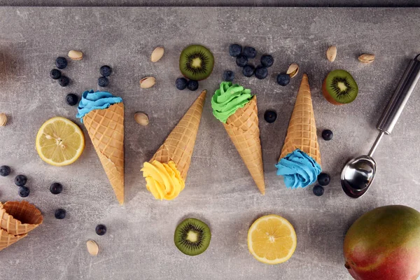 Vanilla frozen yogurt or soft ice cream in waffle cone. Diffrent flavor ice cream with kiwi and pistachio, mango and lemon, blueberry and blackberry