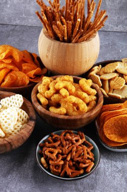 Salty snacks. Pretzels, chips, crackers in wooden bowls. Unhealthy products. food bad for figure, skin, heart and teeth. Assortment of fast carbohydrates food.  clipart