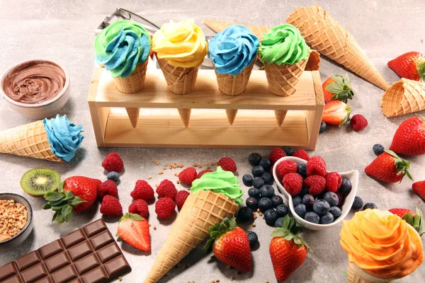 Vanilla frozen yogurt or soft ice cream in waffle cone. Diffrent flavor ice cream with kiwi and pistachio, mango and lemon, blueberry and blackberry