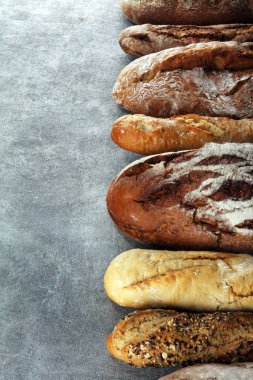 Pişmiş ekmek ve ekmek rulo taş tablo arka plan üzerinde ürün yelpazesine. Fırın poster kavramı