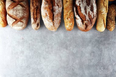Pişmiş ekmek ve ekmek rulo taş tablo arka plan üzerinde ürün yelpazesine. Fırın poster kavramı