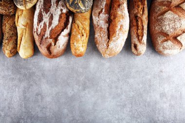 Pişmiş ekmek ve ekmek rulo taş tablo arka plan üzerinde ürün yelpazesine. Fırın poster kavramı