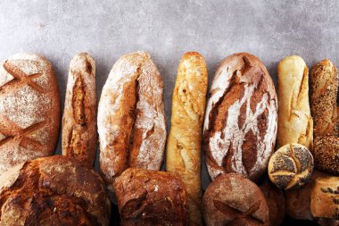 Pişmiş ekmek ve ekmek rulo taş tablo arka plan üzerinde ürün yelpazesine. Fırın poster kavramı