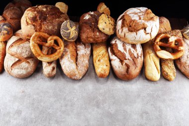 Pişmiş ekmek ve ekmek rulo taş tablo arka plan üzerinde ürün yelpazesine. Fırın poster kavramı