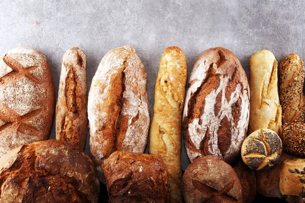 Pişmiş ekmek ve ekmek rulo taş tablo arka plan üzerinde ürün yelpazesine. Fırın poster kavramı