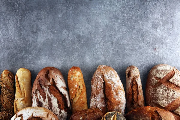 Pişmiş ekmek ve ekmek rulo taş tablo arka plan üzerinde ürün yelpazesine. Fırın poster kavramı
