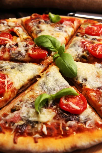 Vegetarian Italian pizza with melted cheese, red tomatoes and green basil on a table decorated by cheese, tomato and red cherry tomatoes