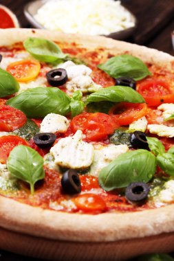 Pizza domates, mozzarella peyniri, Siyah Zeytin ve fesleğen. Lezzetli İtalyan pizza ahşap pizza yönetim kurulu üzerinde. İtalyan pizza