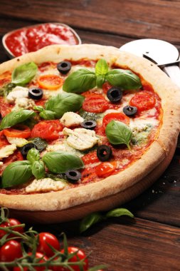 Pizza domates, mozzarella peyniri, Siyah Zeytin ve fesleğen. Lezzetli İtalyan pizza ahşap pizza yönetim kurulu üzerinde. İtalyan pizza