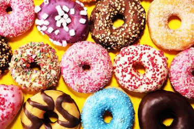 Çikolatalı buzlu, pembe sırlı ve bonibon donuts ile çeşitli çörekler. Karnaval kavramı.