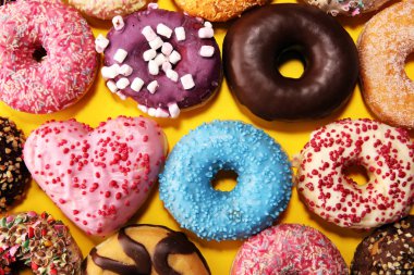 Çikolatalı buzlu, pembe sırlı ve bonibon donuts ile çeşitli çörekler. Karnaval kavramı.