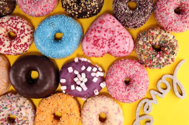 Çikolatalı buzlu, pembe sırlı ve bonibon donuts ile çeşitli çörekler. Karnaval kavramı.
