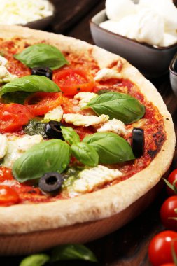 Pizza domates, mozzarella peyniri, Siyah Zeytin ve fesleğen. Lezzetli İtalyan pizza ahşap pizza yönetim kurulu üzerinde. İtalyan pizza