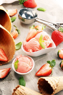 Çilekli dondurma kepçesi taze çilek ve kırsal bir arka planda dondurma külahları.