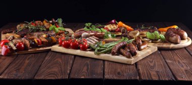 Çeşit çeşit lezzetli ızgara et, sebze ve kırsal masada otlar.