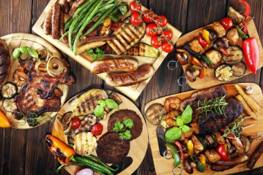 Çeşit çeşit lezzetli ızgara et, sebze ve kırsal masada otlar.