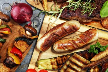 Çeşit çeşit lezzetli ızgara et, sebze ve kırsal masada otlar.