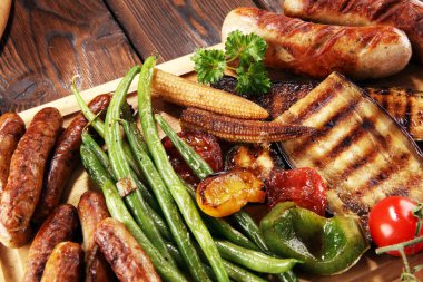 Çeşit çeşit lezzetli ızgara et, sebze ve kırsal masada otlar.