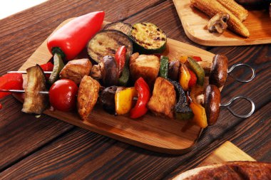 Çeşit çeşit lezzetli ızgara et, sebze ve kırsal masada otlar.