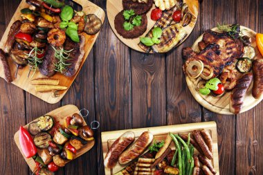 Çeşit çeşit lezzetli ızgara et, sebze ve kırsal masada otlar.