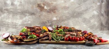 Çeşit çeşit lezzetli ızgara et, sebze ve kırsal masada otlar.