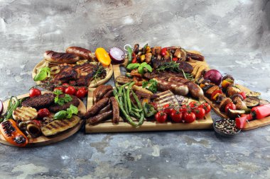 Çeşit çeşit lezzetli ızgara et, sebze ve kırsal masada otlar.