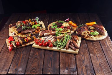 Çeşit çeşit lezzetli ızgara et, sebze ve kırsal masada otlar.