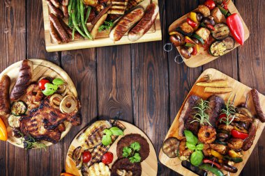 Çeşit çeşit lezzetli ızgara et, sebze ve kırsal masada otlar.