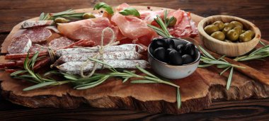 Jambon, pastırma, salam ve sosis ahşap arka plan üzerinde mermer kesme tahtası. Et tabağı meze ve zeytin