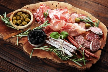 Jambon, pastırma, salam ve sosis ahşap arka plan üzerinde mermer kesme tahtası. Et tabağı meze ve zeytin