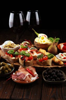 İtalyan antipasti şarap aperatifler küme. Peynir çeşitli, Akdeniz zeytin, turşu, Prosciutto di Parma, domates, enginar ve masada bardaklarda şarap