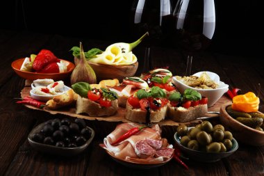İtalyan antipasti şarap aperatifler küme. Peynir çeşitli, Akdeniz zeytin, turşu, Prosciutto di Parma, domates, enginar ve masada bardaklarda şarap