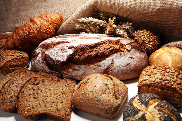 Different kinds of bread and bread rolls on board from above. Kitchen or bakery poster design.