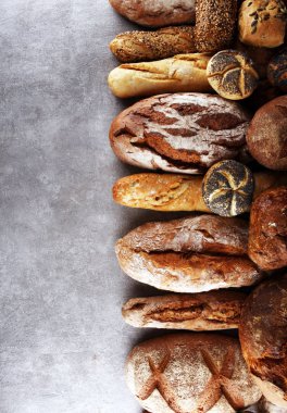 Pişmiş ekmek ve ekmek rulo taş tablo arka plan üzerinde ürün yelpazesine. Fırın poster kavramı