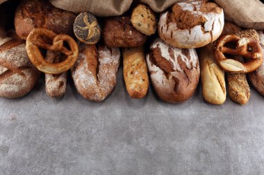 Pişmiş ekmek ve ekmek rulo taş tablo arka plan üzerinde ürün yelpazesine. Fırın poster kavramı