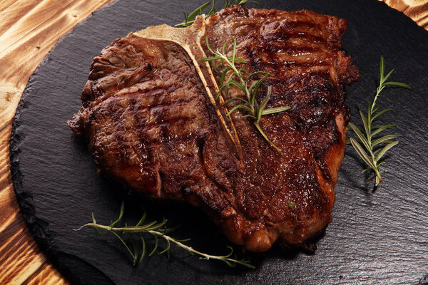 Grilled T-bone steak on stone cutting board.