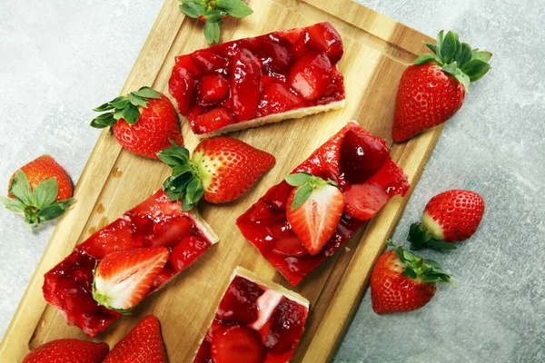 Jordgubbstårta och många färska jordgubbar på grå bakgrund t — Stockfoto