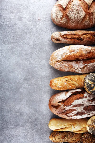 Assortiment van gebakken brood en broodjes op stenen tafel backgro — Stockfoto