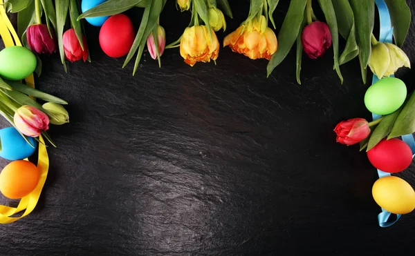 Œufs de Pâques colorés et tulipes sur table rustique — Photo