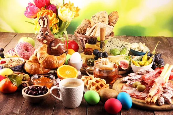 Ontbijt op tafel met eieren, brood, broodjes, croissants en koffie — Stockfoto