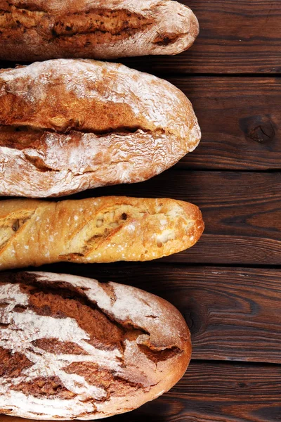 Assortimento di pane e panini da forno su tavola in legno backgr — Foto Stock