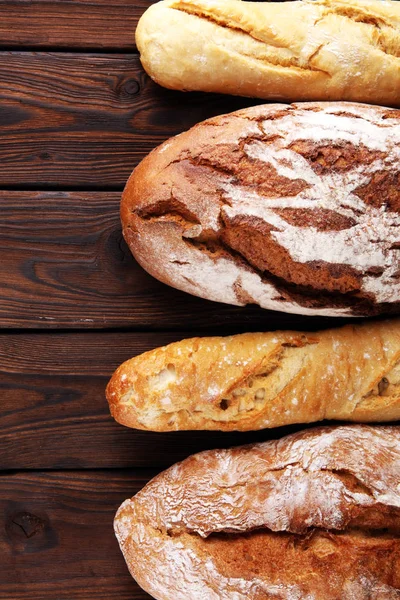 Pişmiş ekmek ve ahşap masa backgr ekmek rulo çeşitleri — Stok fotoğraf