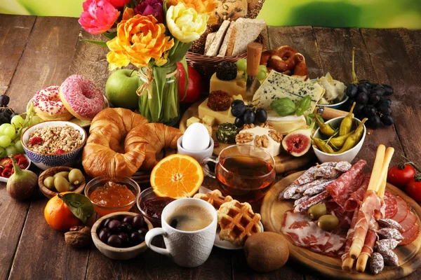 Ontbijt op tafel met eieren, brood, broodjes, croissants en koffie — Stockfoto