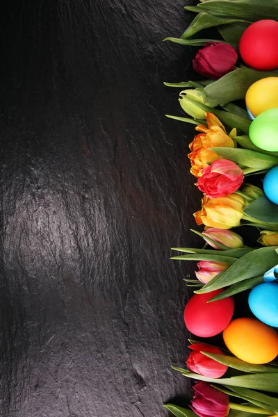 Bunte Ostereier und Tulpen auf rustikalem Tisch — Stockfoto