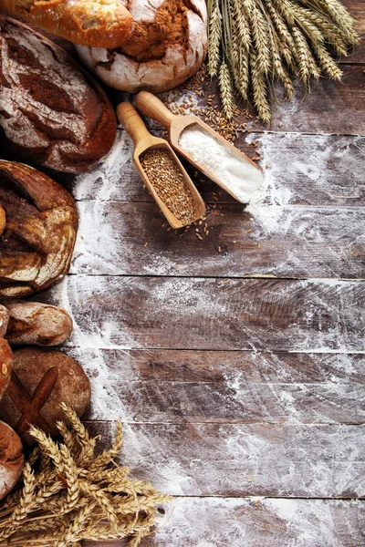 Different kinds of bread and bread rolls on board from above. Ki — Stock Photo, Image