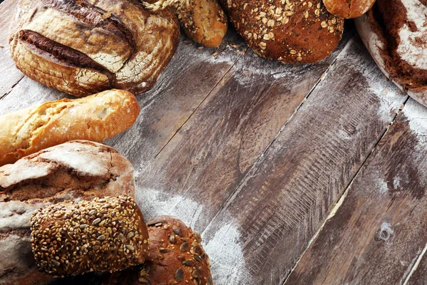 Different kinds of bread and bread rolls on board from above. Ki — Stock Photo, Image