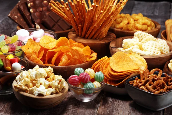 Petiscos salgados. Pretzels, batatas fritas, biscoitos em tigelas de madeira na mesa — Fotografia de Stock